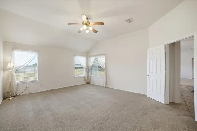 an empty room with chandelier fan and windows