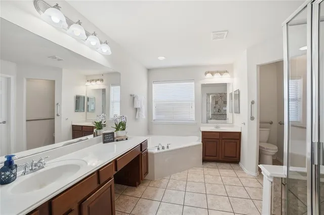 a bathroom with a granite countertop sink a toilet a mirror and bathtub