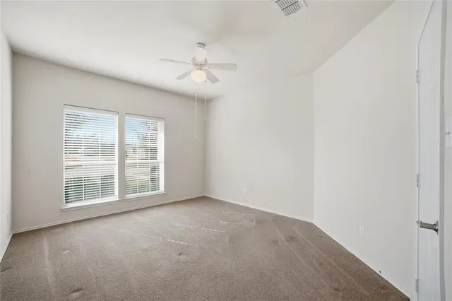 an empty room with windows and fan