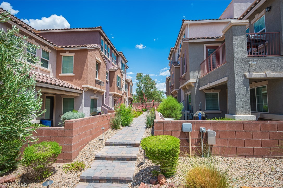 9916 Sable Point Street Las Vegas, NV 89178 - Photo 53 of 73 A charming walkway guides you between two modern townhomes, each featuring a blend of stucco and tiled roofs.