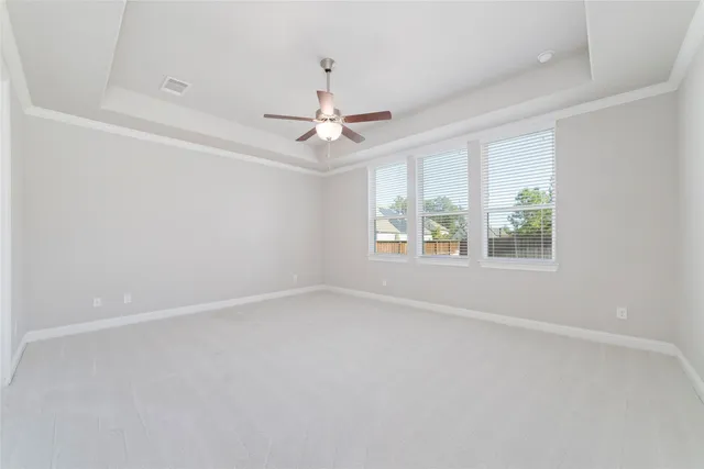 an empty room with windows and chandelier fan