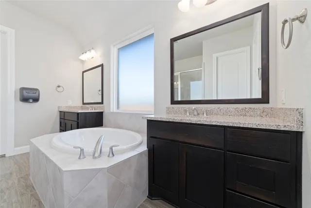 a bathroom with a tub a sink and mirror