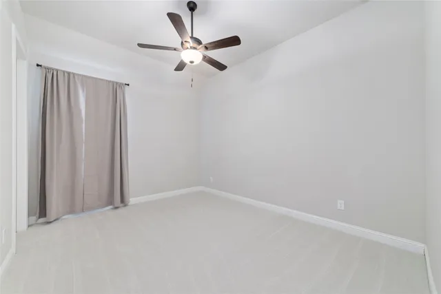 an empty room with a window and ceiling fan