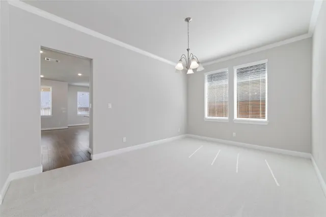 a view of an empty room with window and chandelier fan