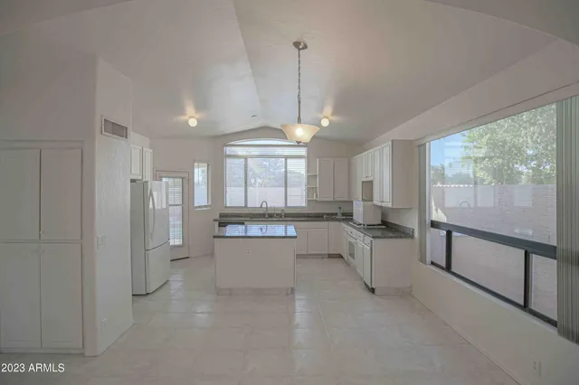 a large hall with stainless steel appliances granite countertop a refrigerator and a sink