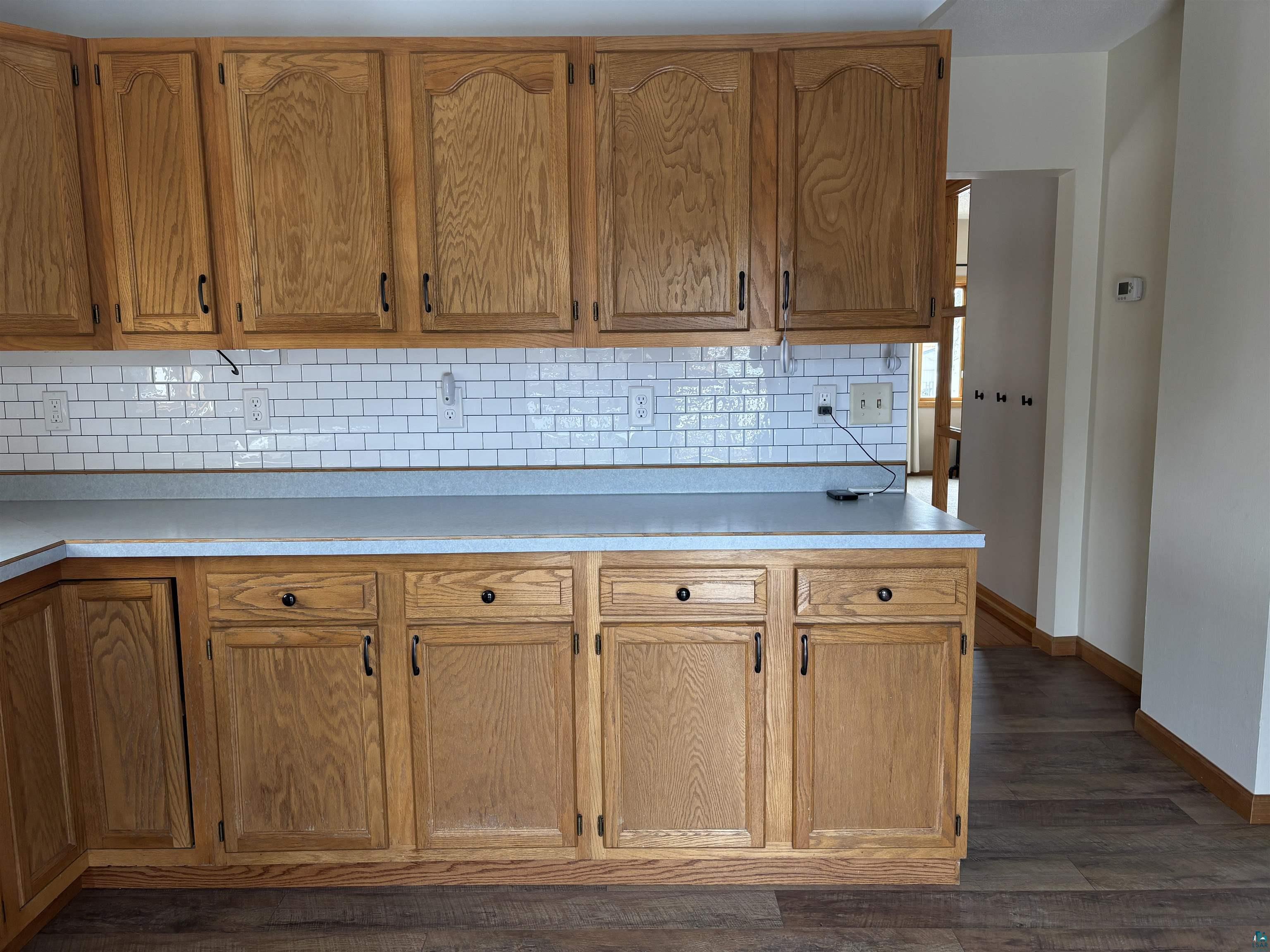 21 4th Street Proctor, MN 55810 - Photo 18 of 35 Kitchen with decorative backsplash, dark wood-style floors, light countertops, and baseboards