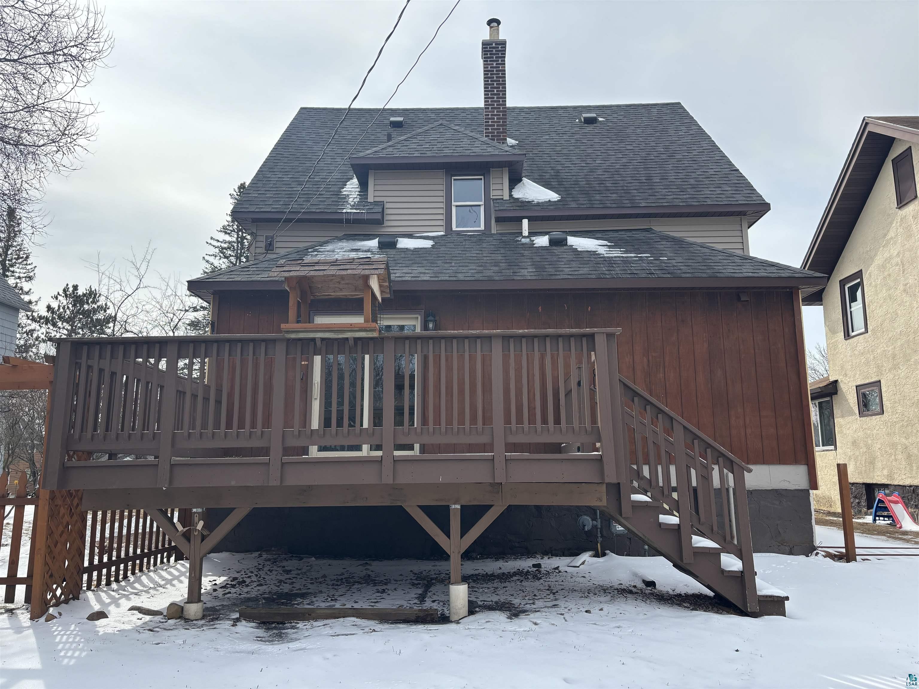 21 4th Street Proctor, MN 55810 - Photo 5 of 35 Snow covered property featuring a chimney, a shingled roof, and a wooden deck