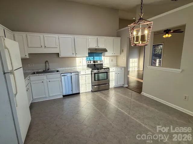 a kitchen with stainless steel appliances granite countertop a sink a stove a refrigerator cabinets and chairs