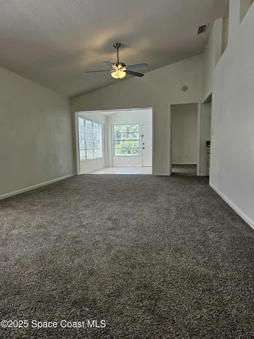 an empty room with windows and chandelier fan