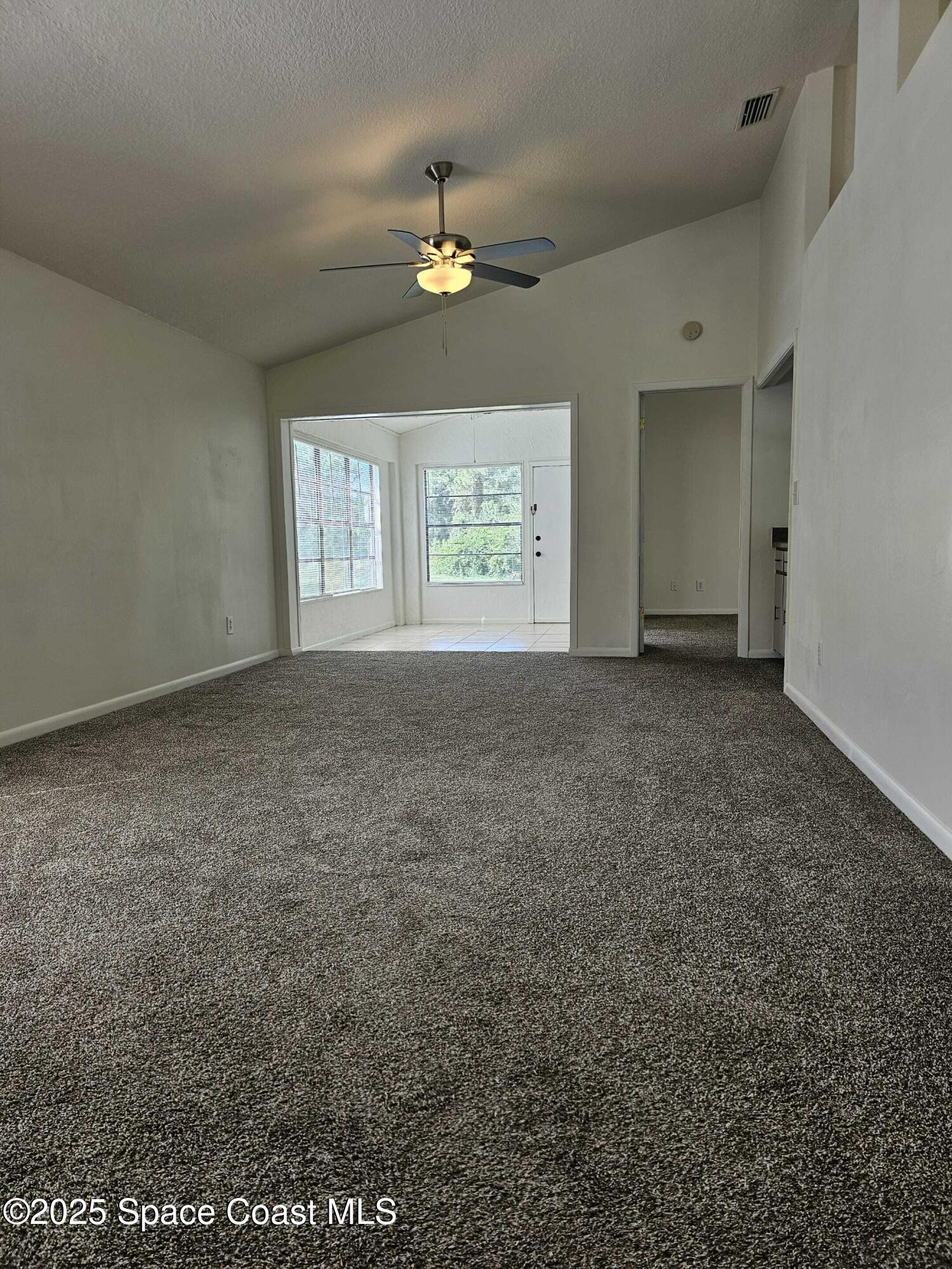 391 Cypress Point Drive Melbourne, FL 32940 - Photo 17 of 28 an empty room with windows and chandelier fan