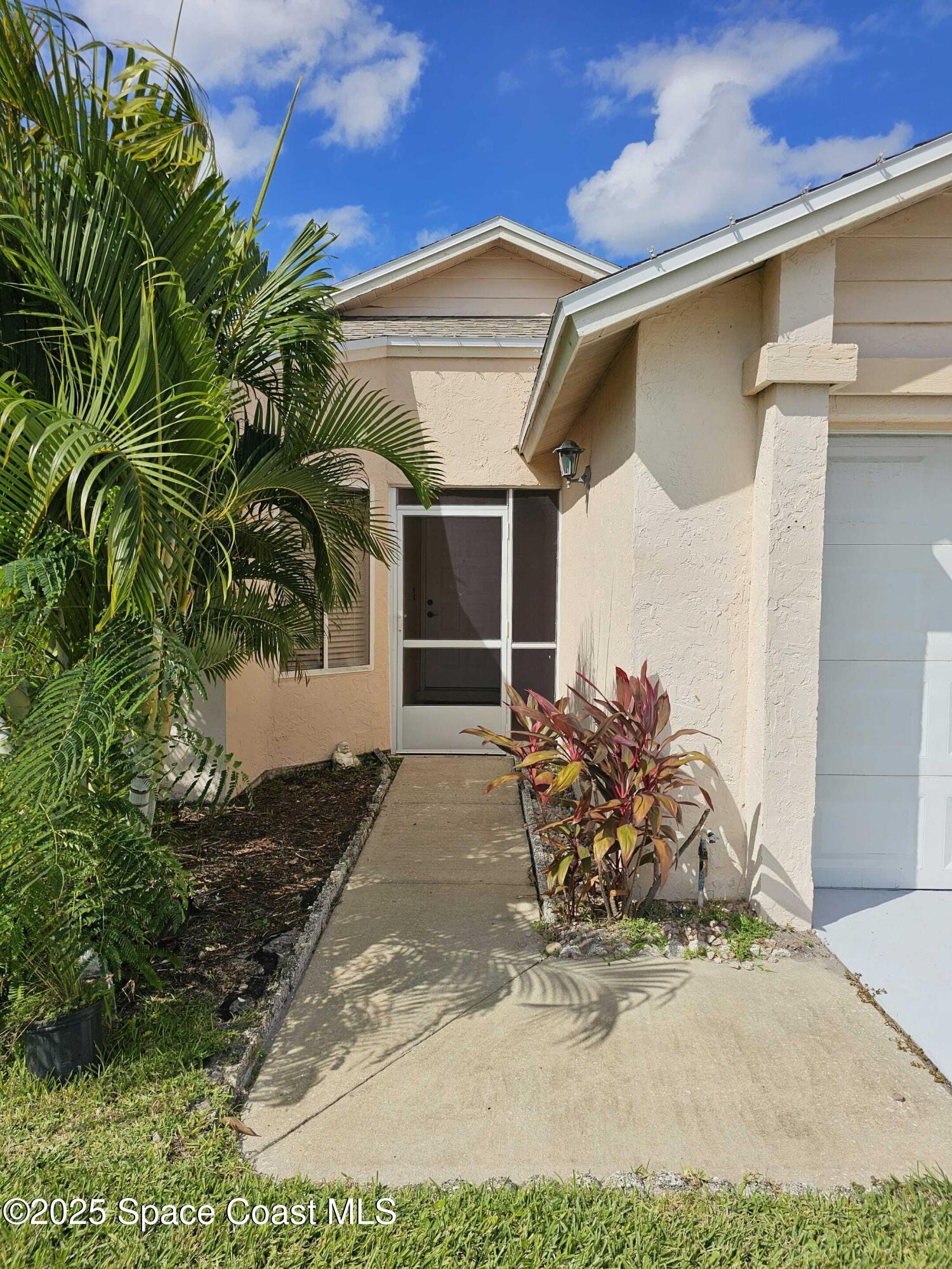 391 Cypress Point Drive Melbourne, FL 32940 - Photo 2 of 28 a front view of a house with a yard and garage