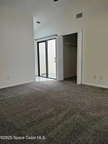 a view of an empty room with closet and a window
