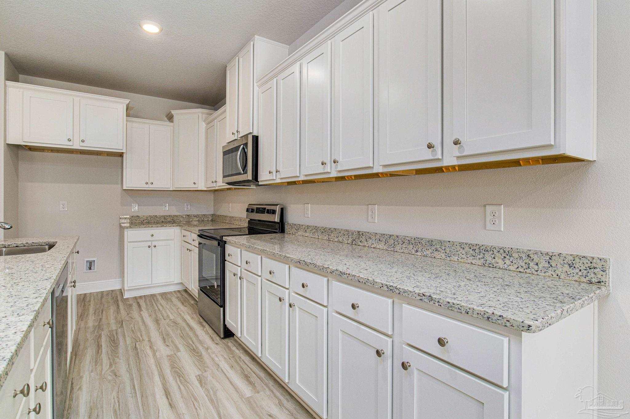 3152 Silver Maple Drive Cantonment, FL 32533 - Photo 14 of 25 a kitchen with granite countertop white cabinets and white appliances