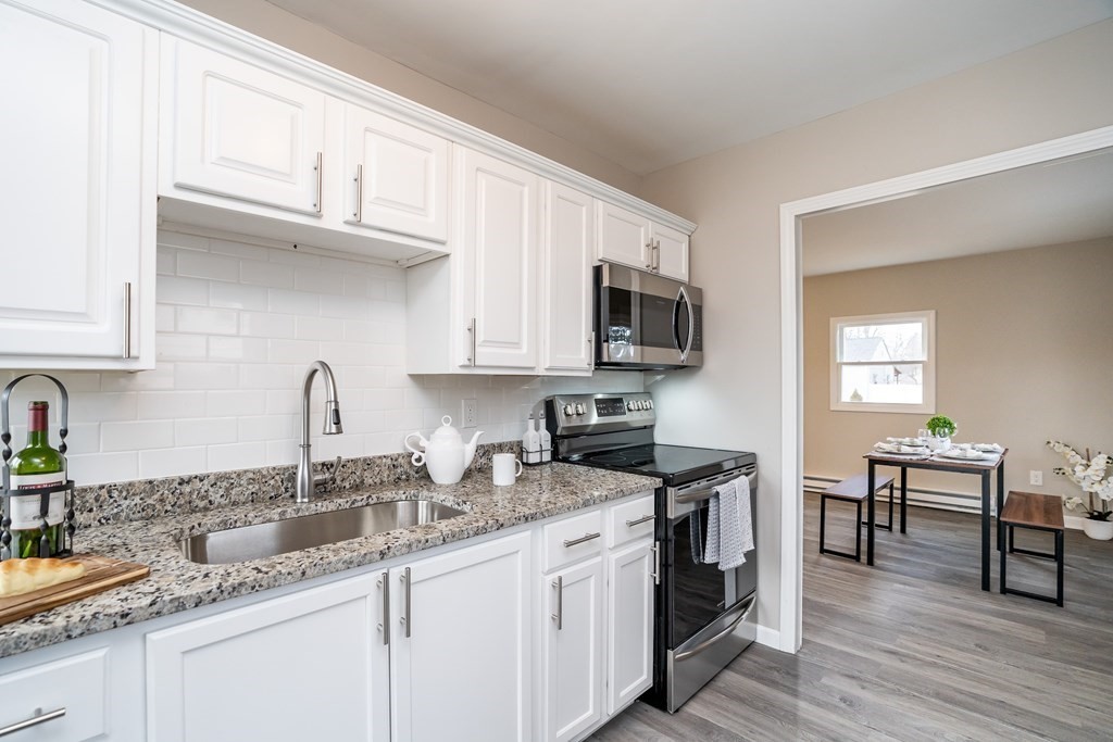 27 Ansara Street Springfield, MA 01104 - Photo 5 of 30 a kitchen with stainless steel appliances granite countertop a sink dishwasher a stove top oven a dining table and chairs with wooden floor