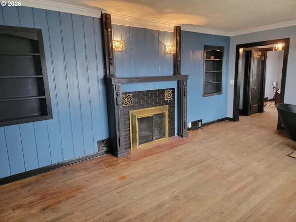 a view of an empty room with wooden floor and a fireplace