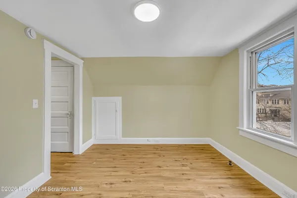 a view of an empty room with window and wooden floor