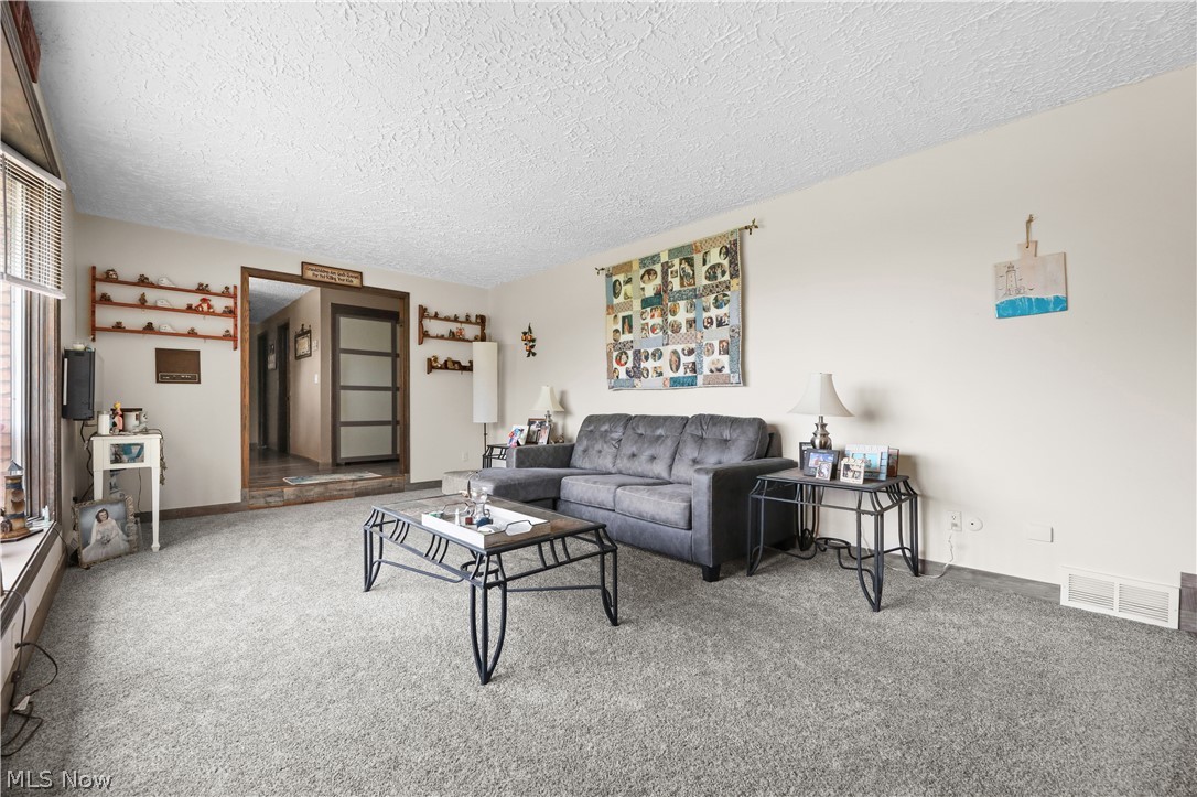 1761 May Road Mogadore, OH 44260 - Photo 4 of 46 Spacious carpeted room featuring a large window, recessed hallway access, and neutral wall tones