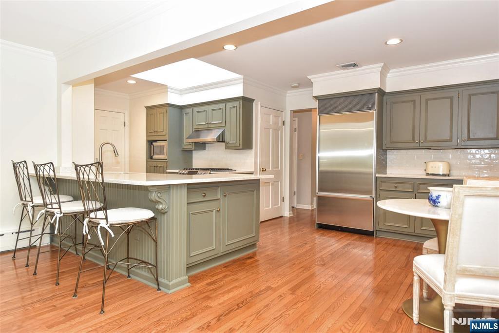 60 Dimmig Road Upper Saddle River, NJ 07458 - Photo 16 of 40 a kitchen with stainless steel appliances kitchen island granite countertop a refrigerator a stove a sink and white cabinets with wooden floor