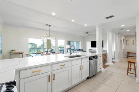 a kitchen with kitchen island granite countertop a sink and white cabinets