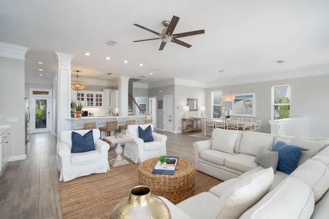 a living room with furniture kitchen view and a wooden floor