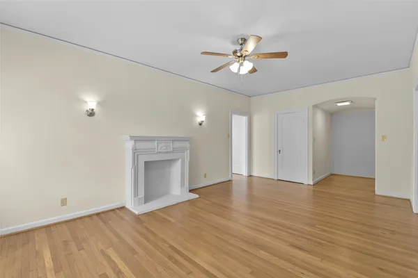 an empty room with wooden floor chandelier fan and windows