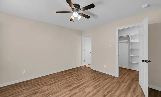 an empty room with wooden floor and ceiling fan