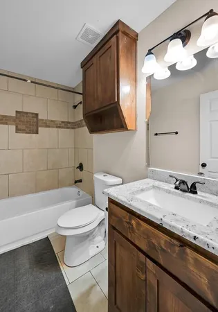 a bathroom with a granite countertop sink a toilet and bathtub