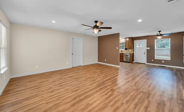 a view of an empty room with window and wooden floor