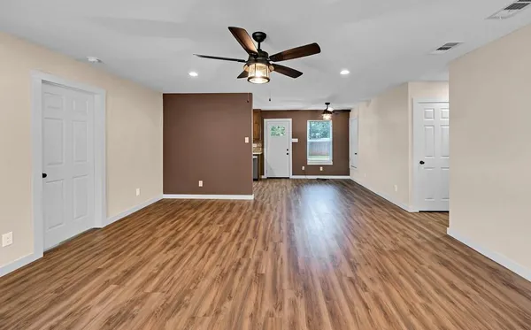 a view of empty room with wooden floor and ceiling fan