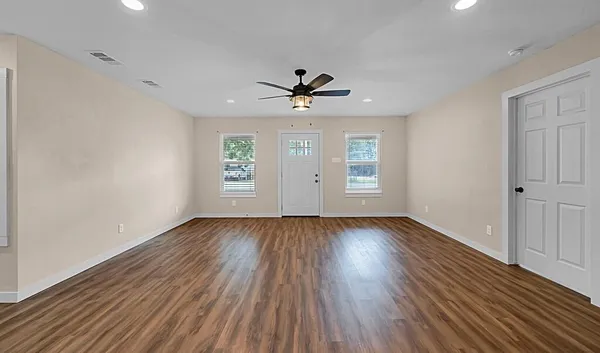 an empty room with wooden floor and windows