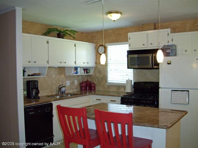 5108 South Bonham Street Amarillo, TX 79110 - Photo 4 of 13 a kitchen with stainless steel appliances granite countertop a stove top oven a sink a refrigerator and a microwave