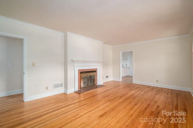 a view of empty room with wooden floor and fireplace