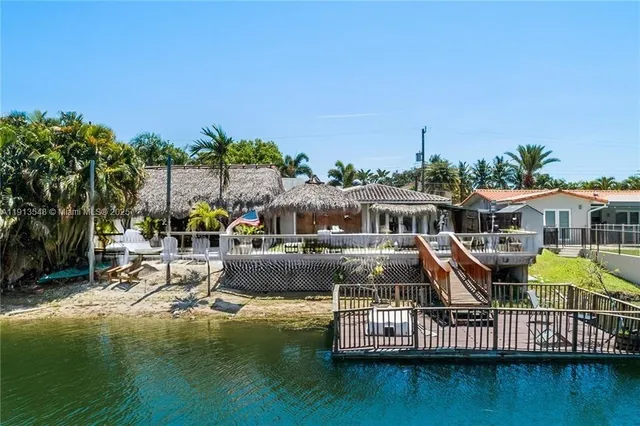 a view of a patio with a dining table and chairs under an umbrella with a small yard