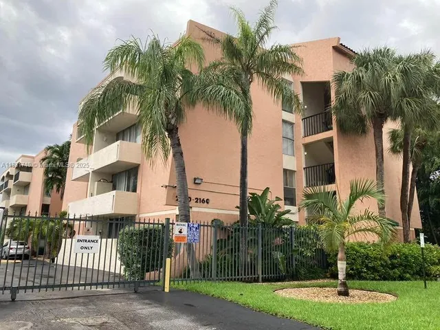 a front view of multi story residential apartment building with yard and green space