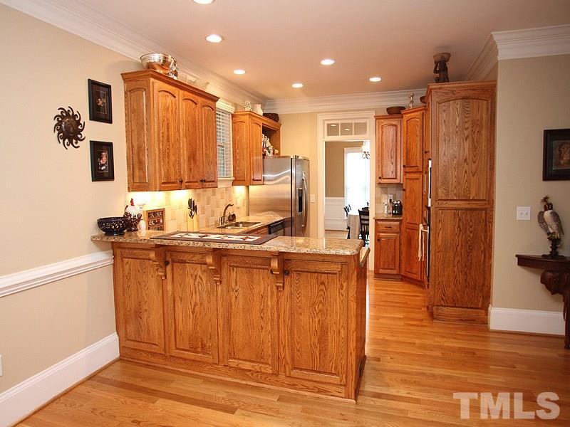 3710 Congeniality Way Raleigh, NC 27613 - Photo 5 of 23 Cook's kitchen with granite, tile backsplash, hardwoods, crown molding, gas cooktop, built in wall oven and microwave.