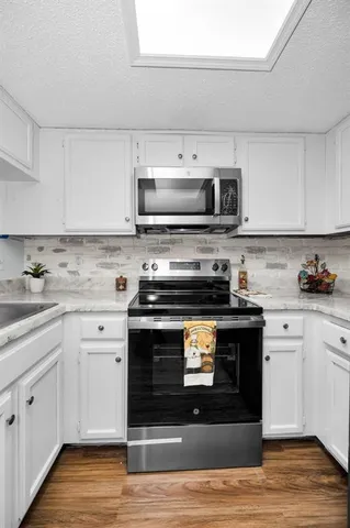 a kitchen with stainless steel appliances granite countertop a stove a sink and a microwave