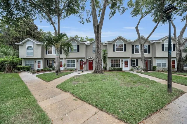 a front view of a house with a garden and tree