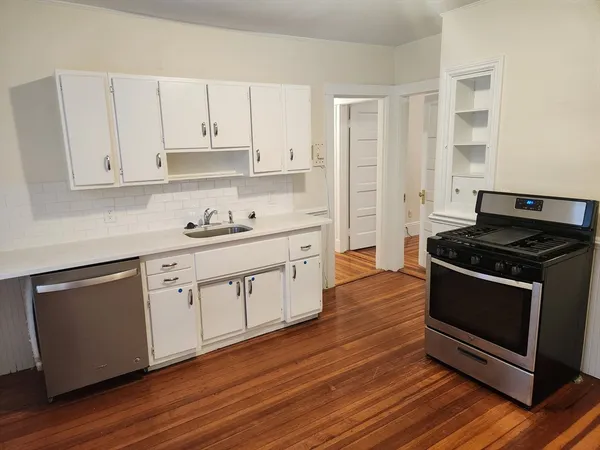 a kitchen with stainless steel appliances white cabinets and a stove a oven with wooden floor