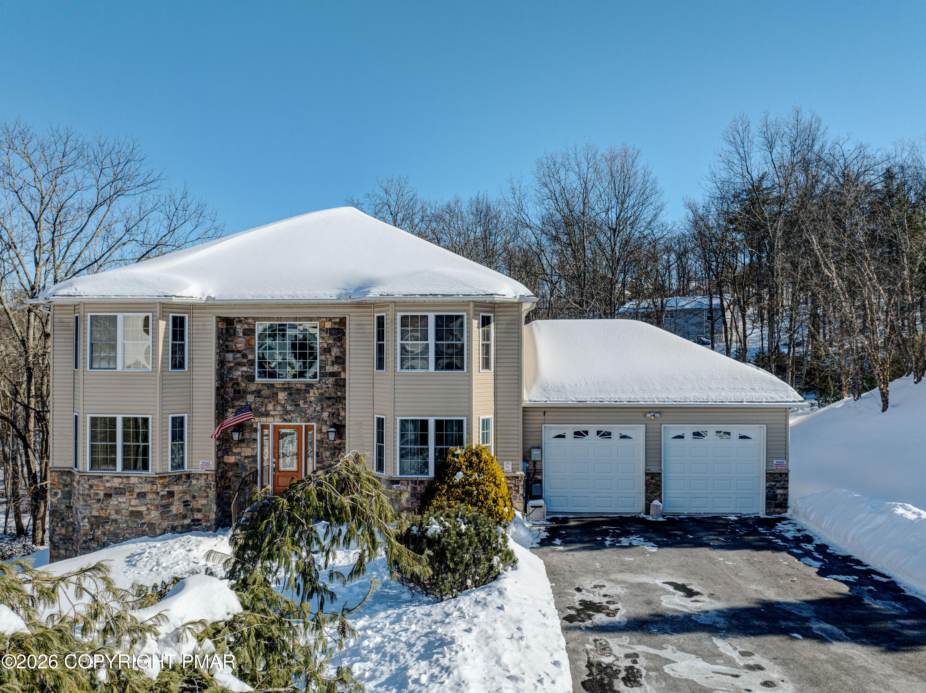 a view of a white house with a small yard plants and large tree