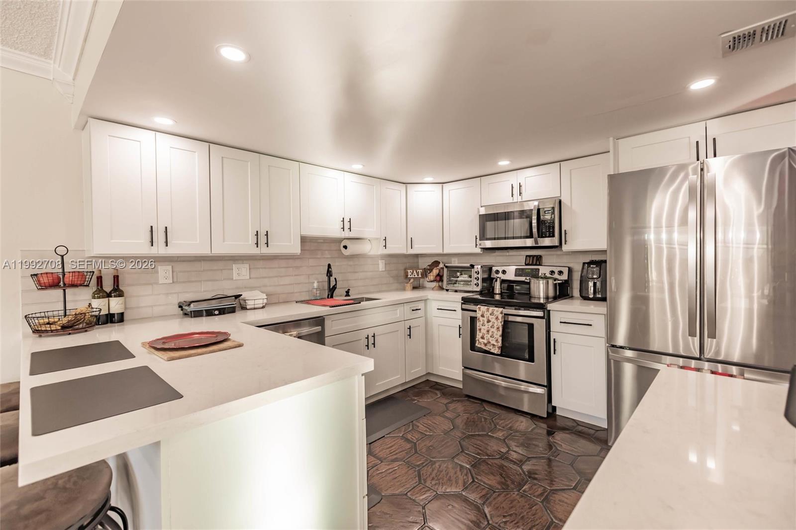 9404 Southwest 8th Terrace, Unit 9404 Miami, FL 33174 - Photo 19 of 41 a kitchen with a sink a stove a refrigerator and white cabinets