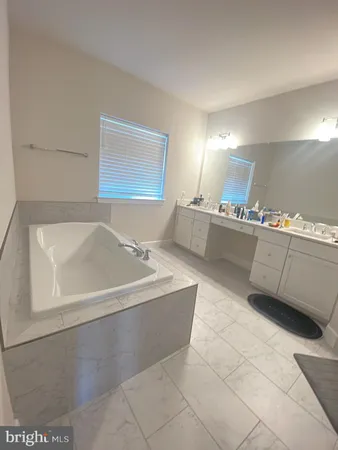 a spacious bathroom with a tub sink and mirror