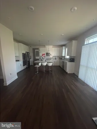 a living room with stainless steel appliances a wooden floor a rug and a window