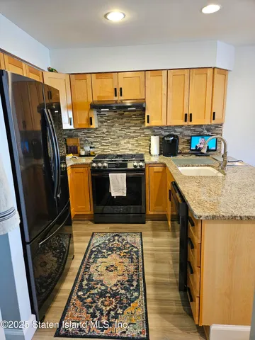 a kitchen with stainless steel appliances granite countertop a stove top oven a sink and a granite counter tops with a large window