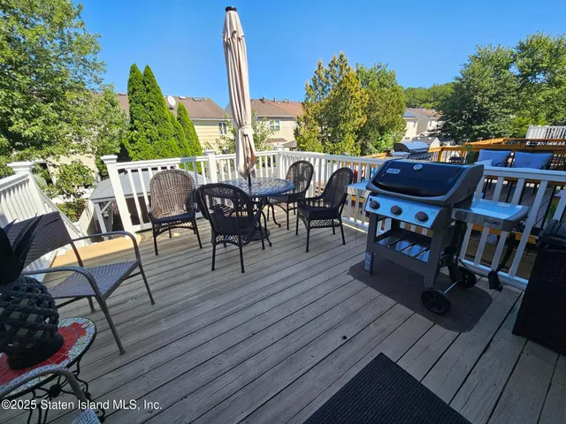a view of a patio with table and chairs with wooden floor and fence