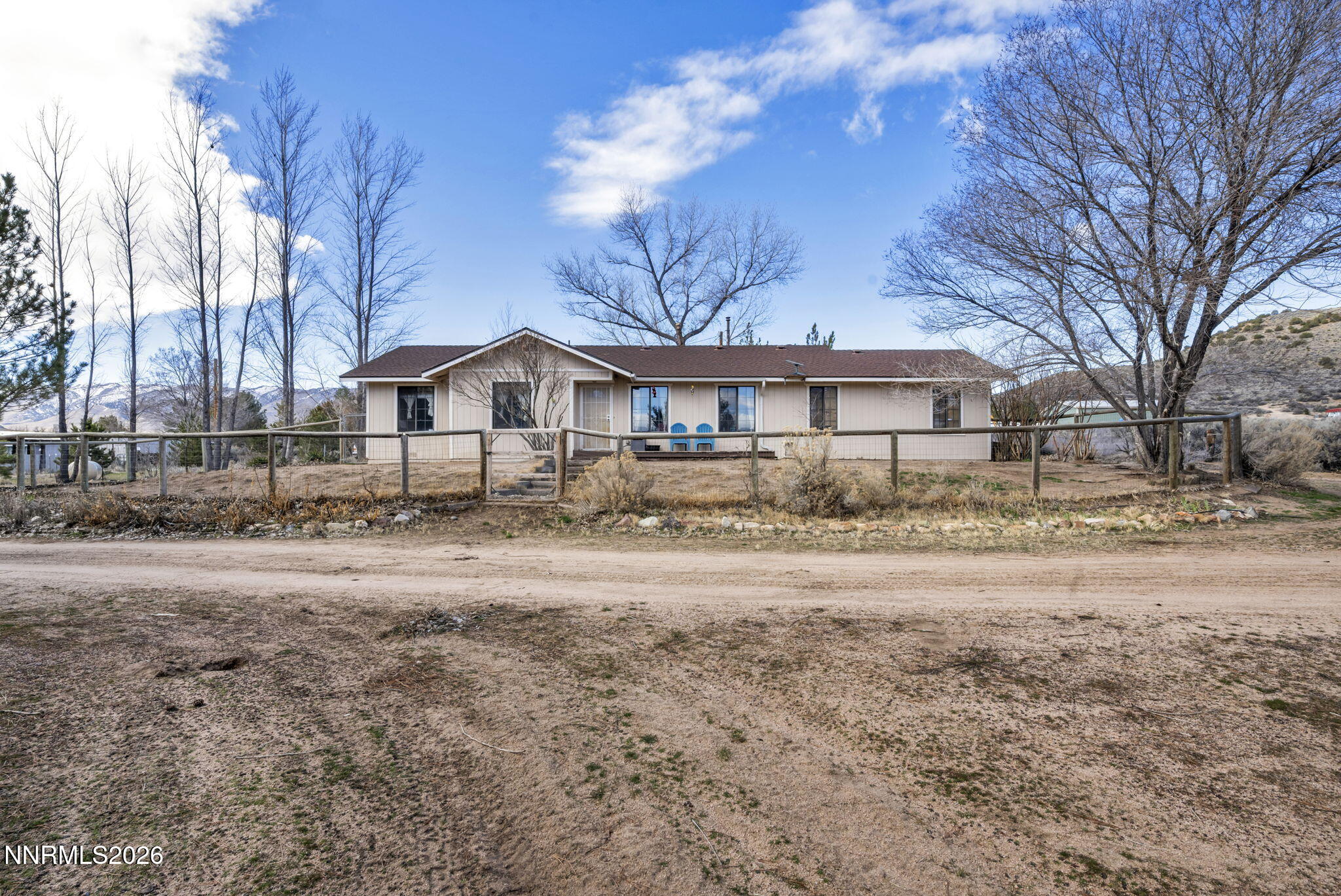 a front view of a house with a dirt yard and a large tree