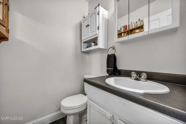 a bathroom with a granite countertop toilet sink and mirror