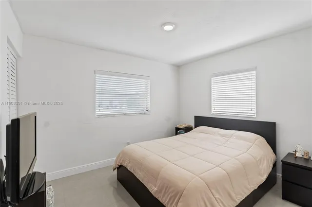 a bedroom with a bed tv and a window