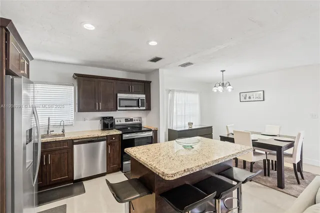 a kitchen with a stove a sink a dining table and chairs