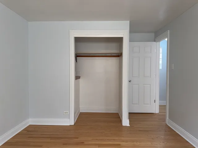a view of empty room with wooden floor and closet