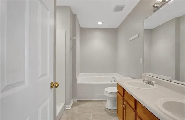 a bathroom with a bathtub shower sink vanity mirror and toilet
